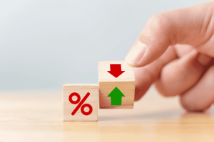 Hand flipping a wooden block showing up and down arrows next to a percentage symbol.