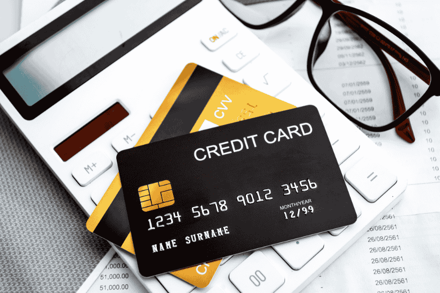 Black credit card and calculator on financial documents with reading glasses